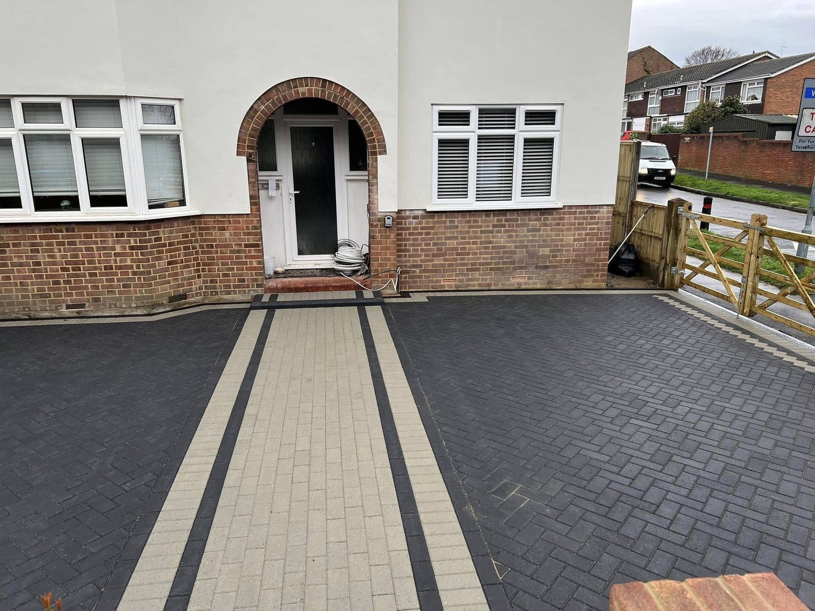 Charcoal block driveway with a buff soldier course leading to an arched brick porch