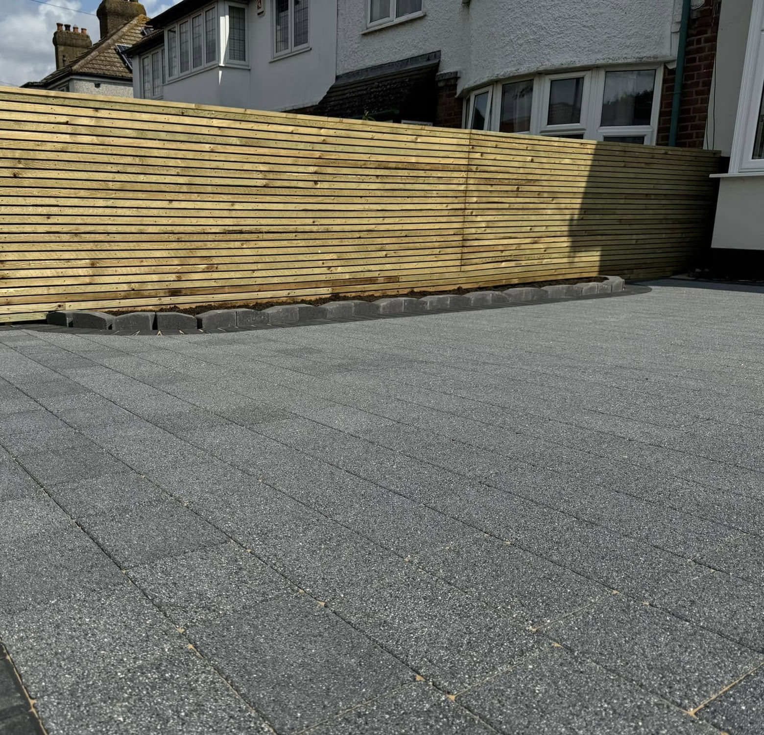 Charcoal block paving driveway with a horizontal timber slat fence