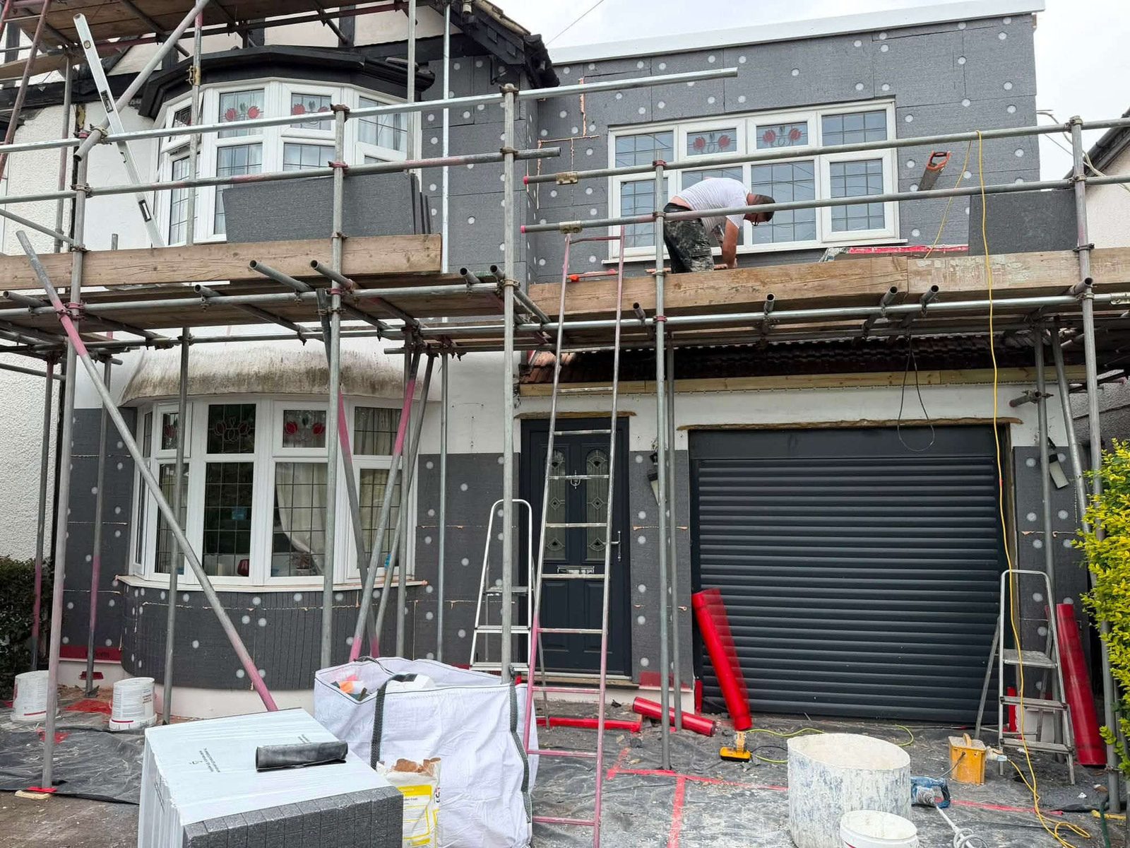 Full elevation covered in insulation boards with a worker on the scaffold