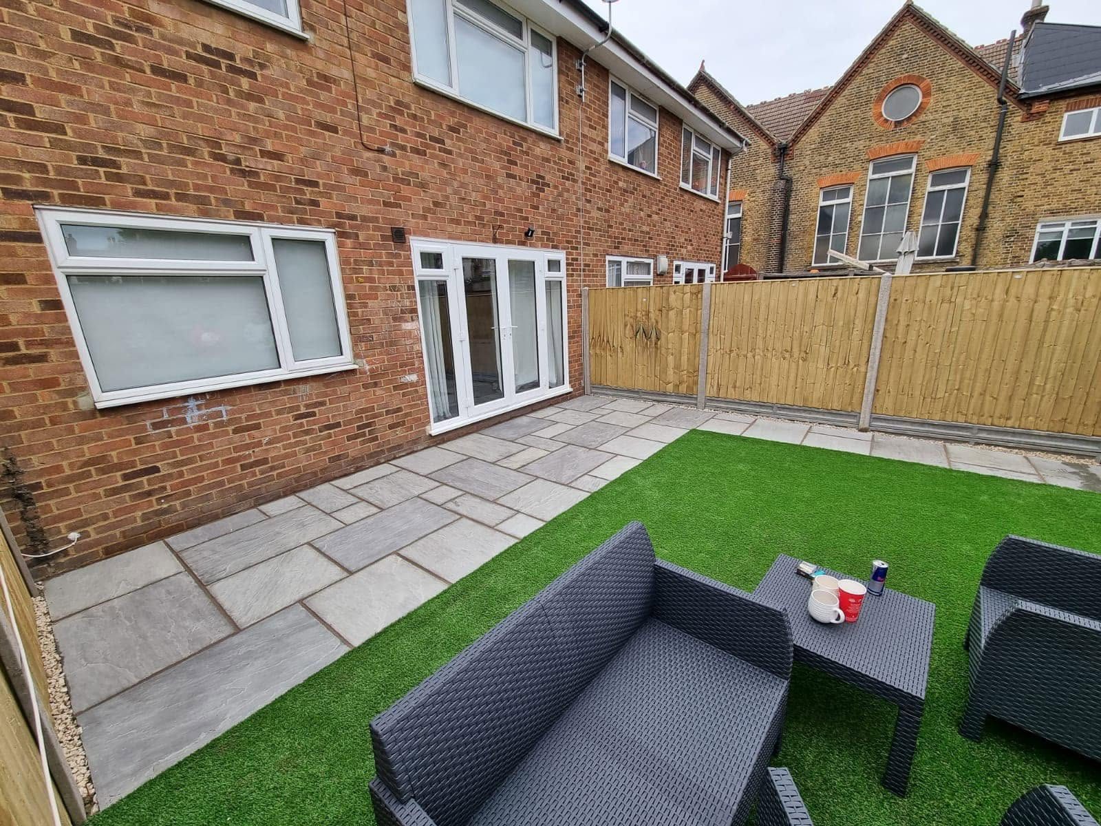 Rear garden with a sandstone patio, artificial grass and rattan seating