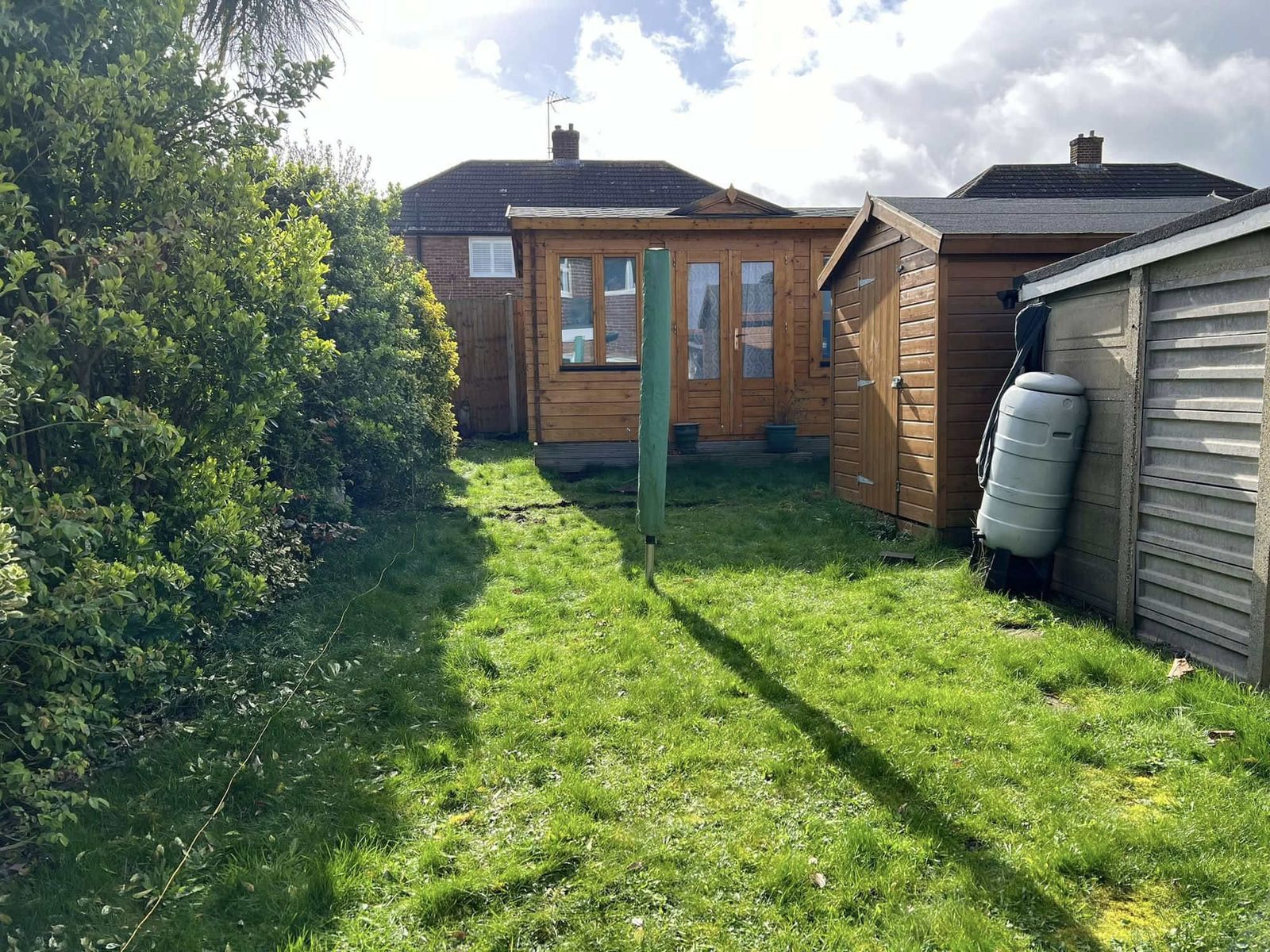 Rough lawn running down the garden to a timber summerhouse before the work