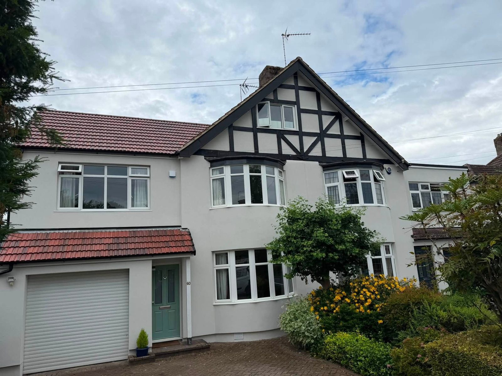 Semi-detached house finished in white silicone render with a brick herringbone driveway