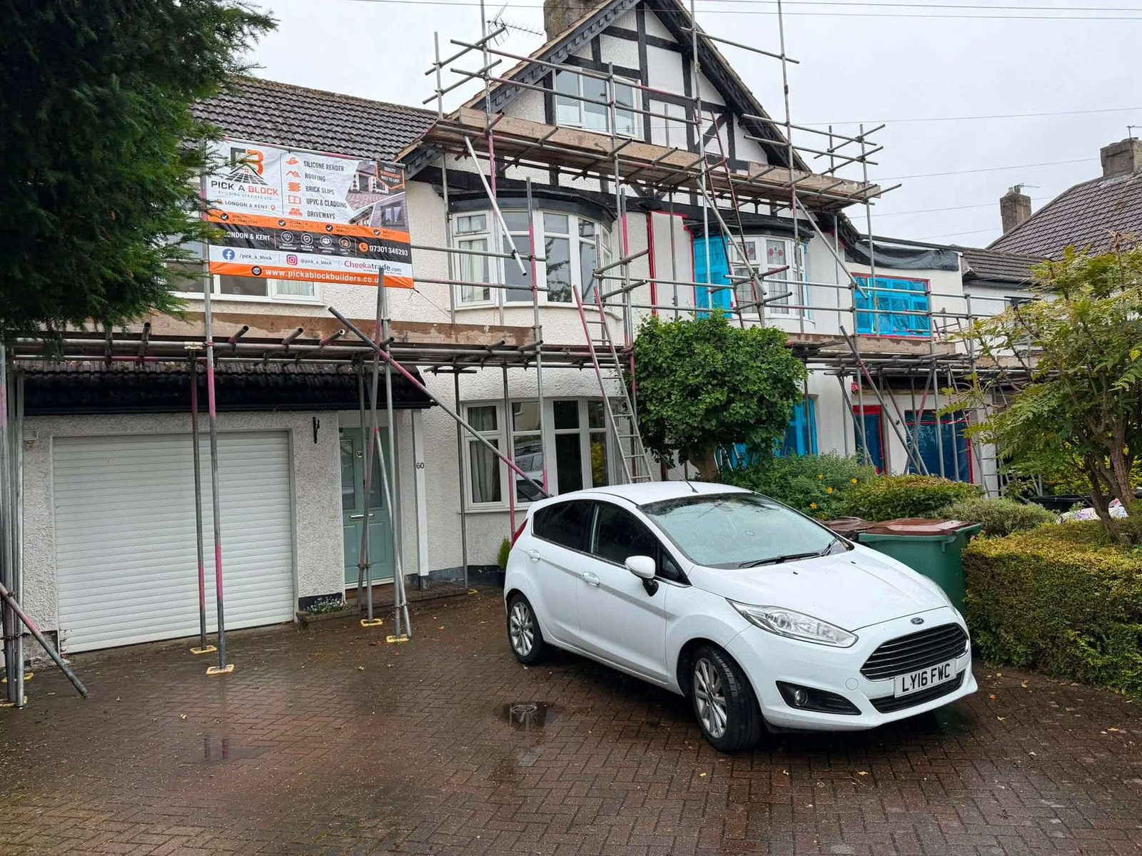Semi-detached house mid-job with scaffold up, windows taped and insulation boards being fixed