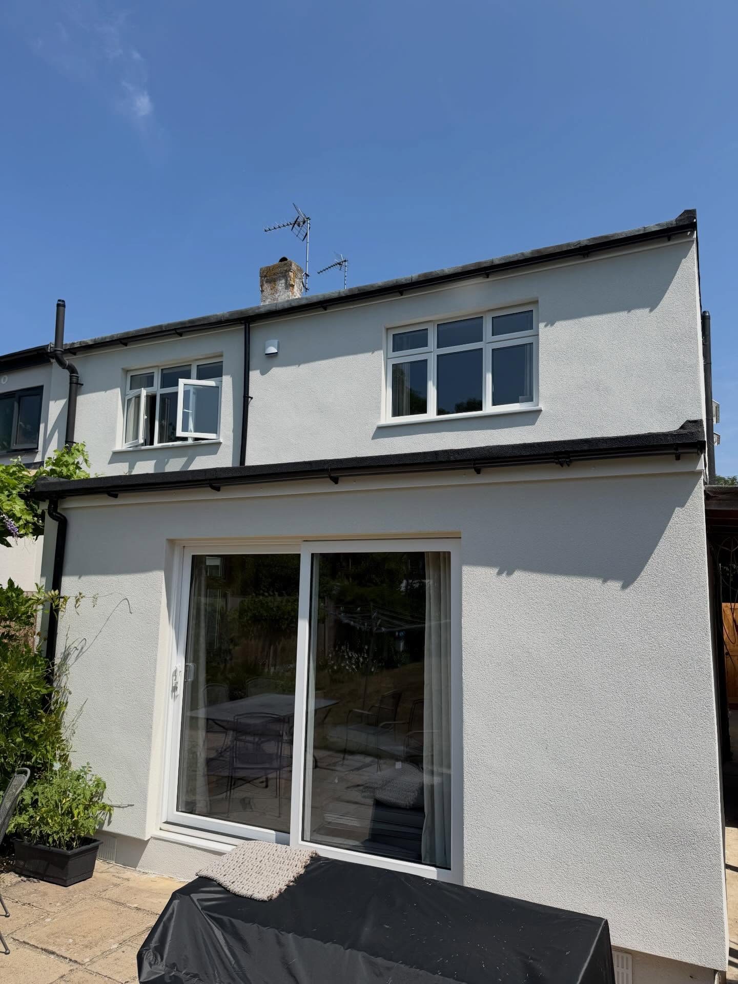 Rear elevation in white silicone render with white sliding patio doors