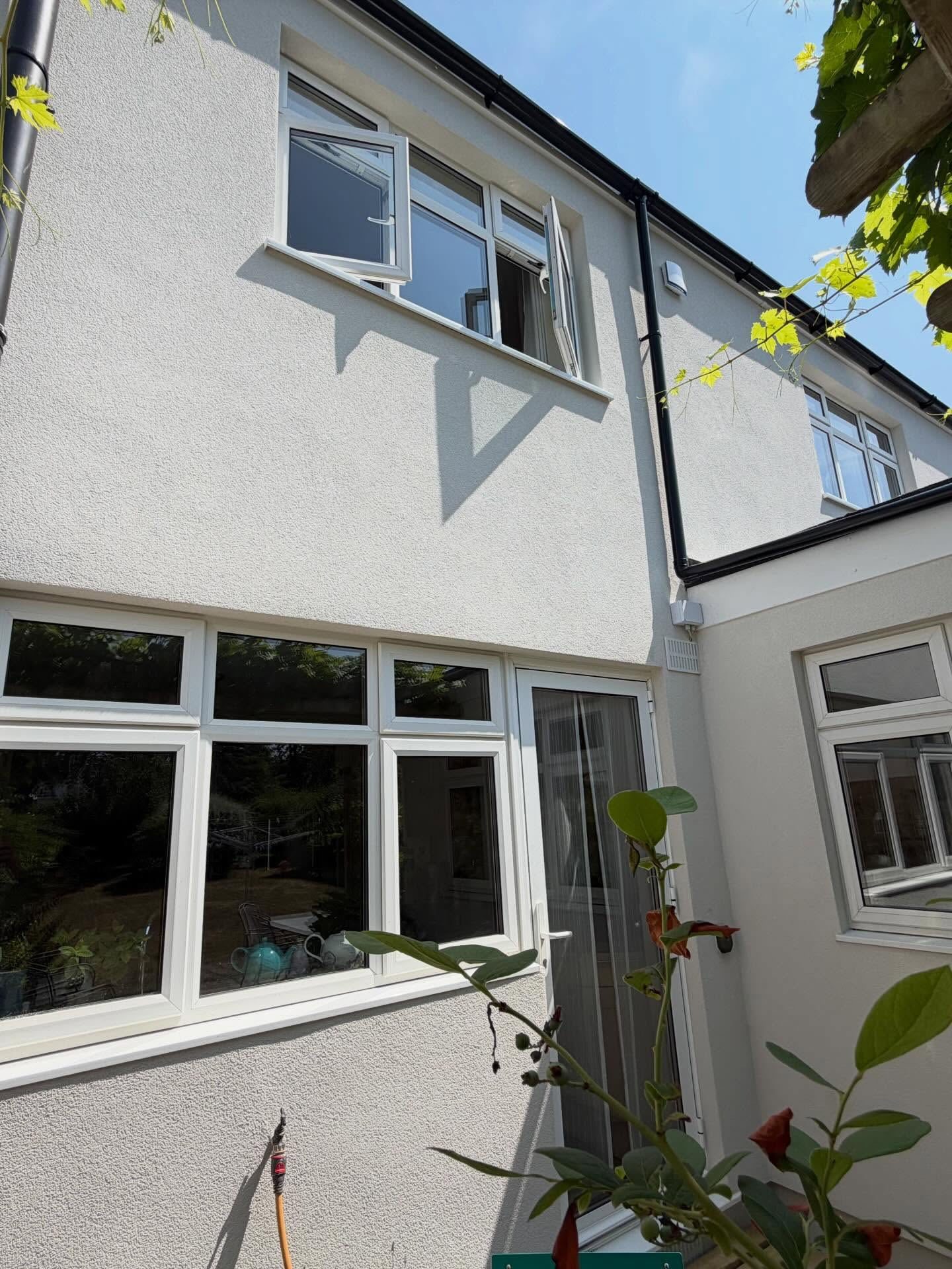 Rear of a house finished in white silicone render under a clear blue sky