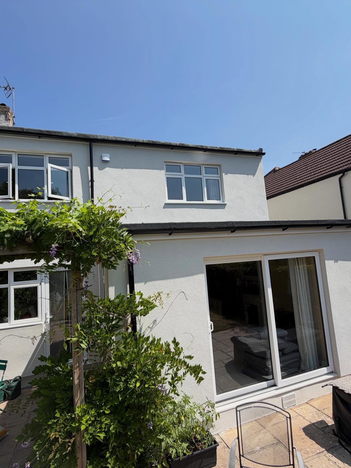 Rear elevation in white silicone render behind a wisteria pergola
