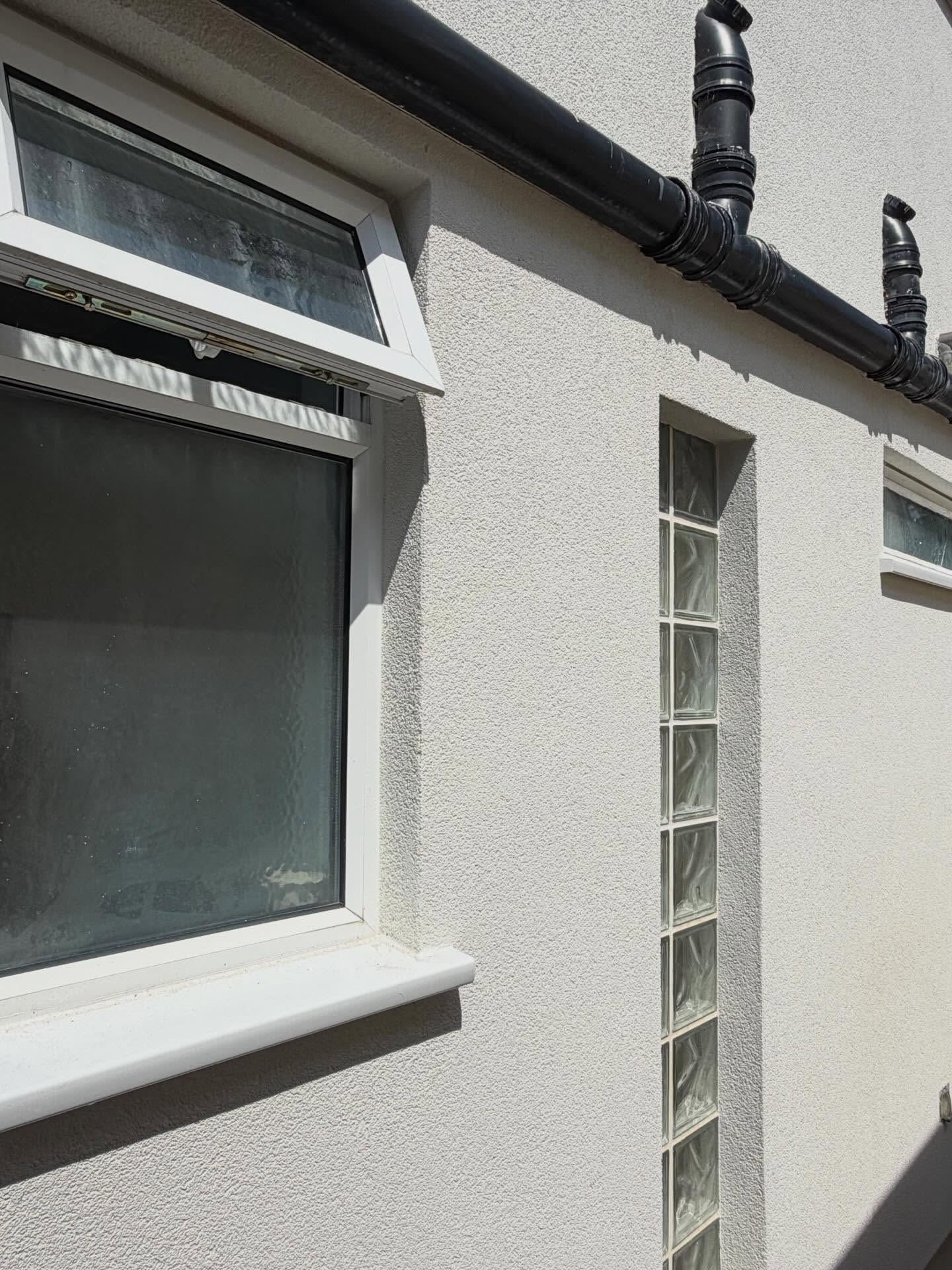 Close view of the silicone render texture beside a glass block panel in strong sun