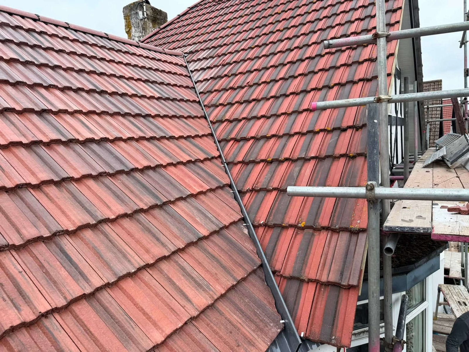 Newly re-tiled roof section meeting the existing roof with new leadwork in the valley